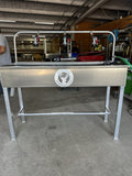 Aluminum cleaning station with raised trough and spray nozzles.