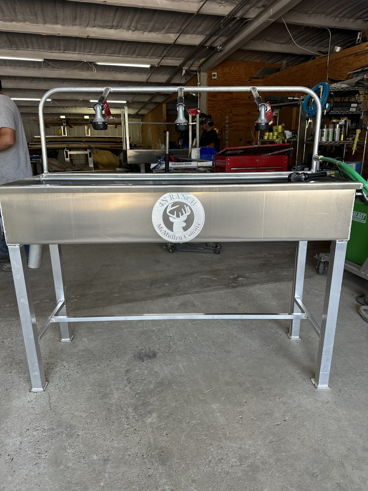 Aluminum cleaning station with raised trough and spray nozzles.
