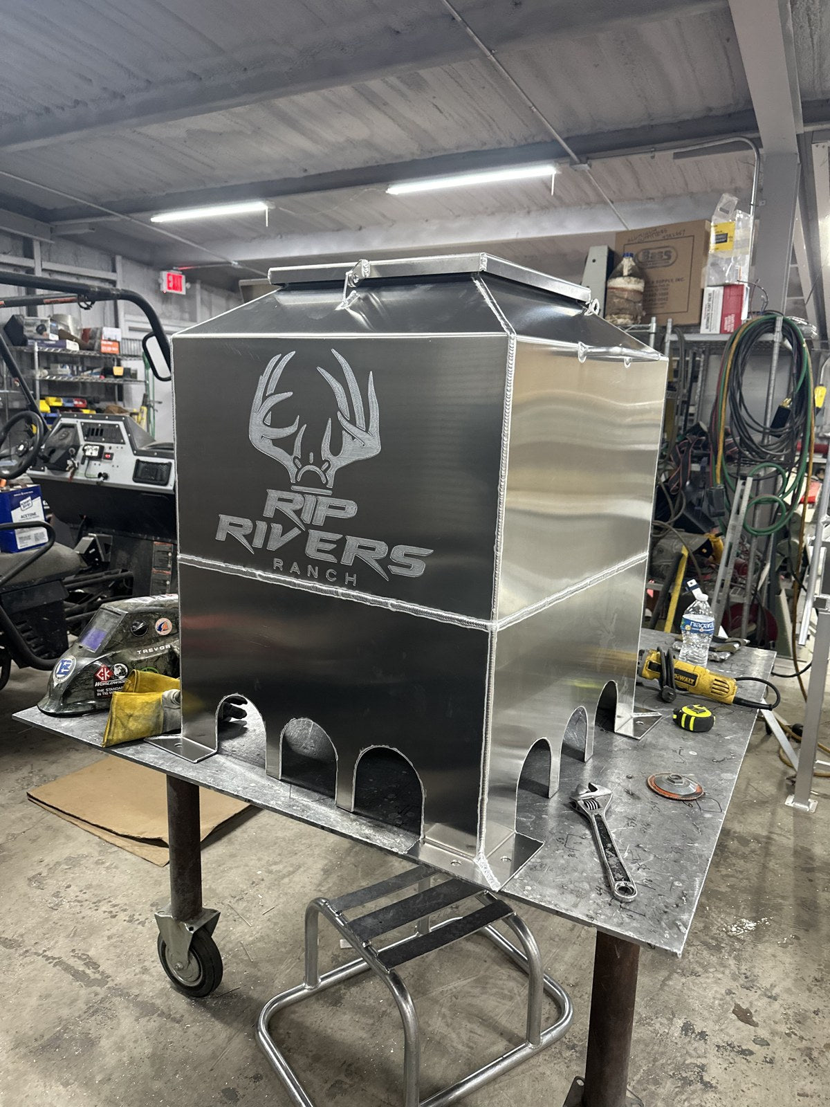 Aluminum quail feeder on legs with a laser-cut ranch logo.